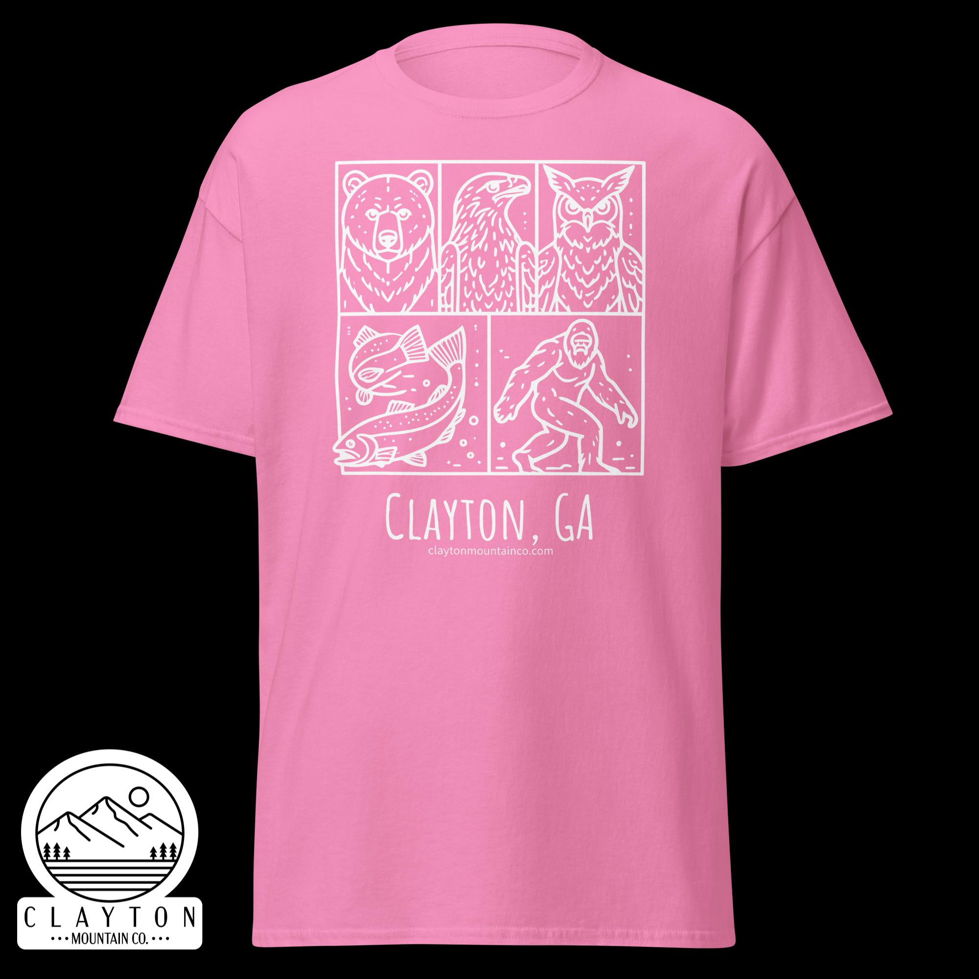 unisex-classic-tee-azalea-front-6a2e6635a2574jpg - Clayton Mountain Co. Pink t-shirt featuring a white comic panel design with a bear, an eagle, and an owl, plus outdoor icons and the text 'Clayton, GA' and 'claytonmountainco.com' underneath. A partial round sticker with mountains appears at the bottom left.