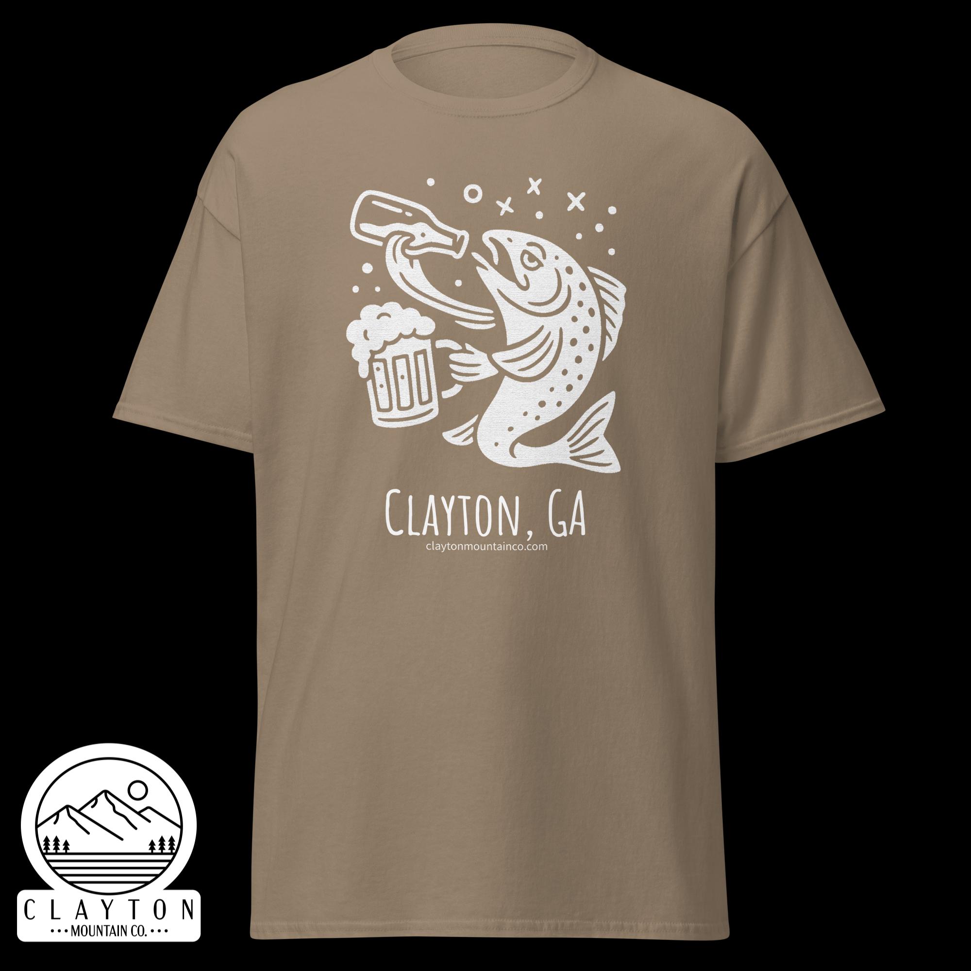unisex-classic-tee-brown-savana-front-6a2e5d8995849jpg - Clayton Mountain Co. Beige T-shirt with a white line drawing of a fish grabbing a beer mug, plus a round sticker logo showing mountains and 'Clayton Mountain Co.' branding.