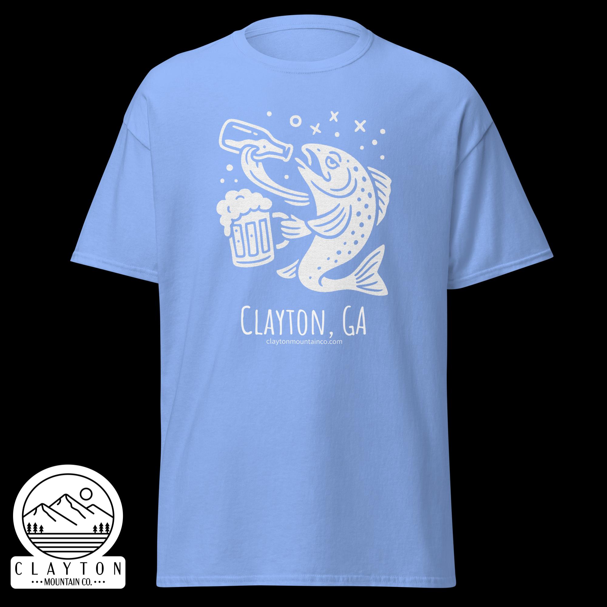 unisex-classic-tee-carolina-blue-front-6a2e5d8999572jpg - Clayton Mountain Co. Blue t-shirt featuring a white line art graphic of a jumping fish holding a beer mug, with mountains in a circular badge and text reading 'Clayton, GA' and a website at the bottom.