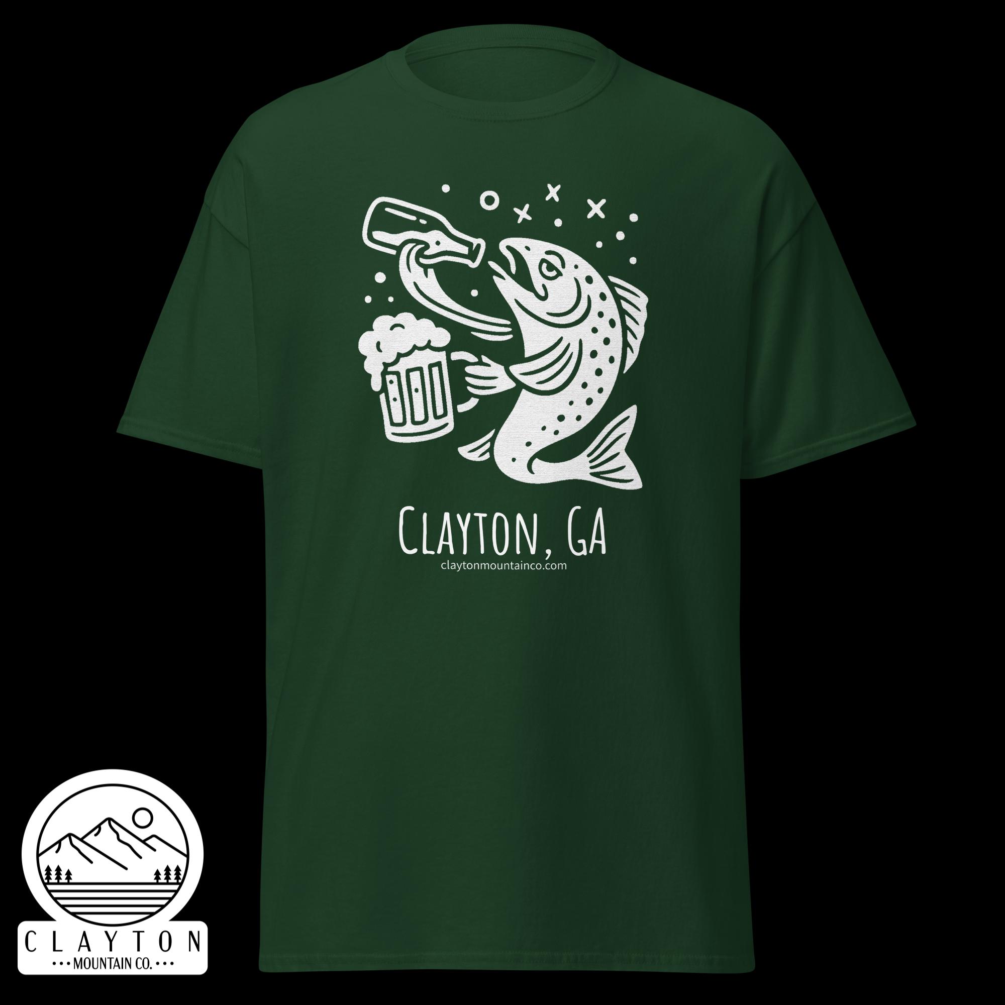 unisex-classic-tee-forest-green-front-6a2e5d89aef7ajpg - Clayton Mountain Co. Green T‑shirt with a white line drawing of a fish leaping toward a beer mug, surrounded by bubbles, and a circular Clayton Mountain Co. logo at the bottom left edge of the image.