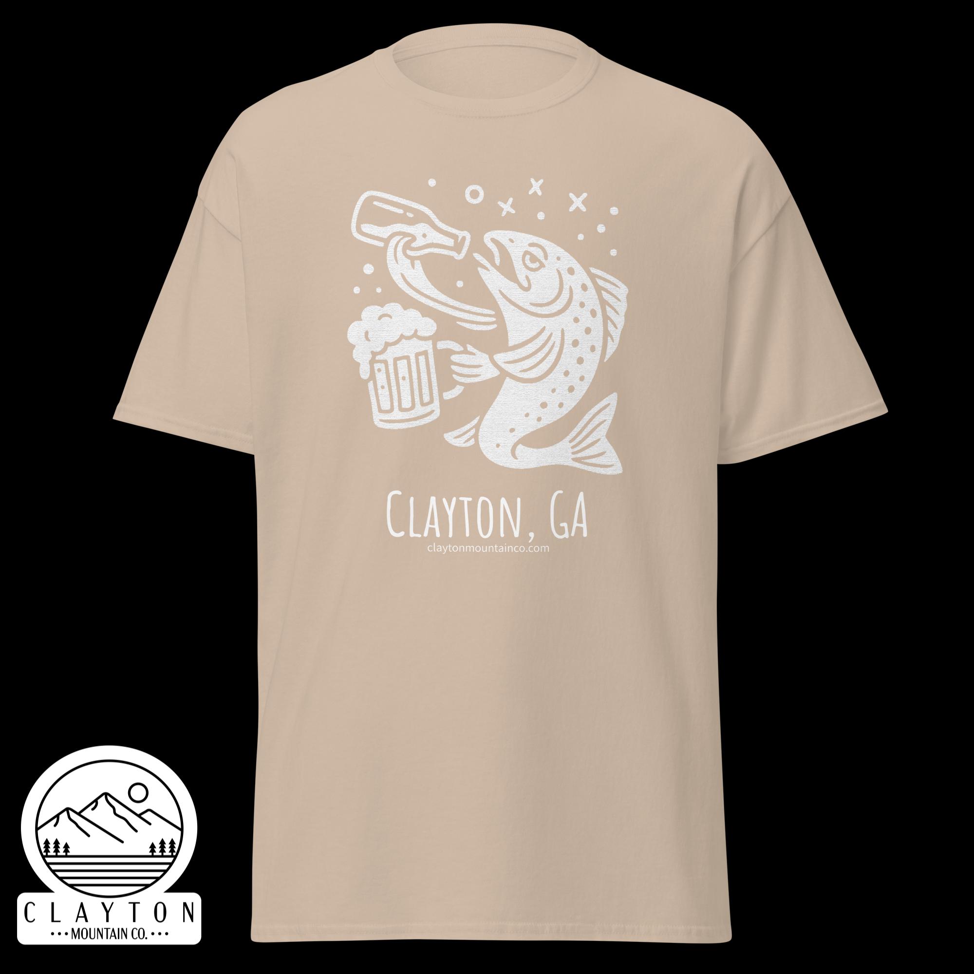 unisex-classic-tee-sand-front-6a2e5d89ace4djpg - Clayton Mountain Co. Beige T-shirt with a white line drawing of two fish toasting a beer mug, bubbles around, and text reading Clayton, GA with a mountain logo sticker at the bottom left.