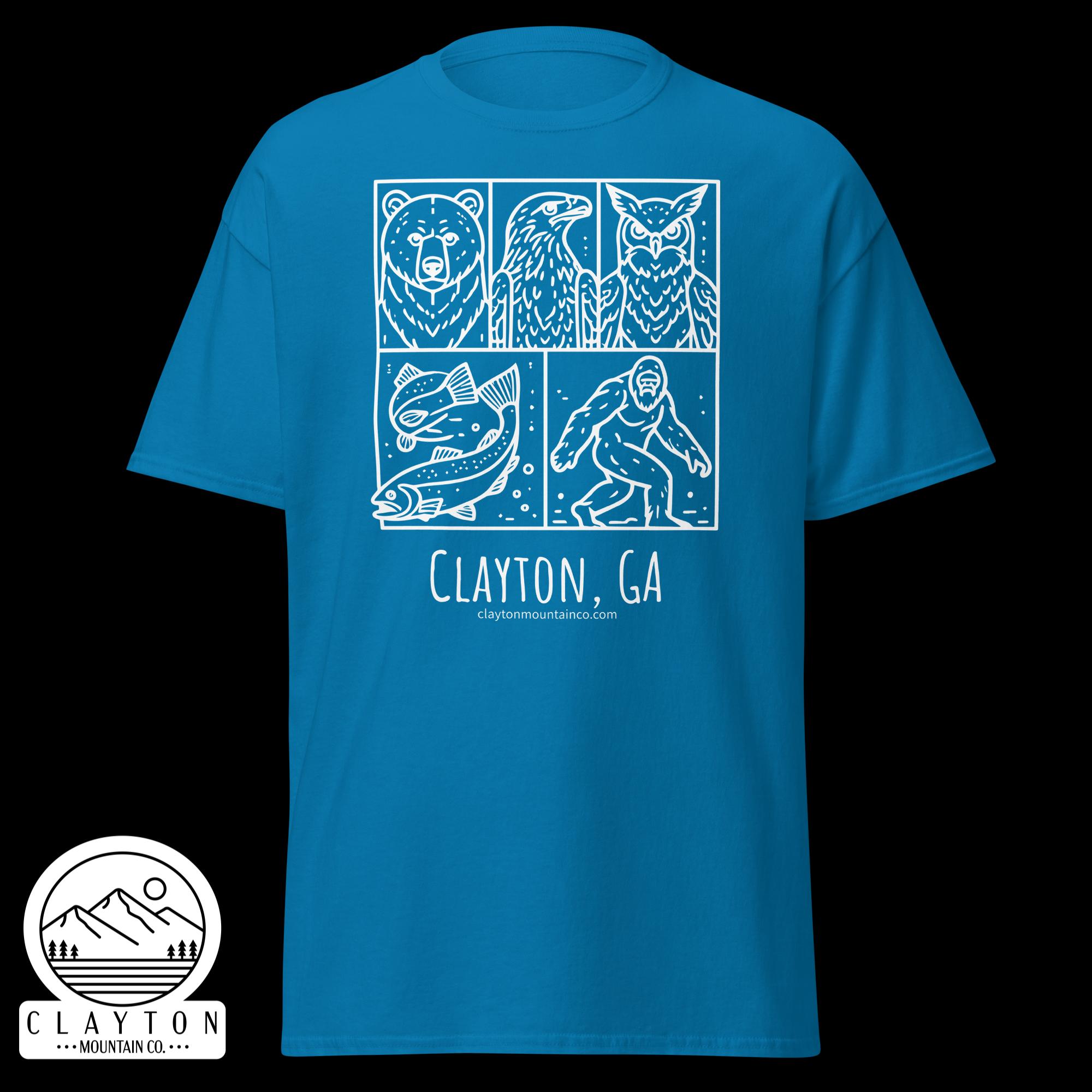 unisex-classic-tee-sapphire-front-6a2e6635b4b84jpg - Clayton Mountain Co. Blue t-shirt displaying a white comic-style panel featuring a bear, bird, and owl, with a fish and a bearded figure at bottom, plus text 'CLAYTON, GA' and a mountain logo at the bottom left.