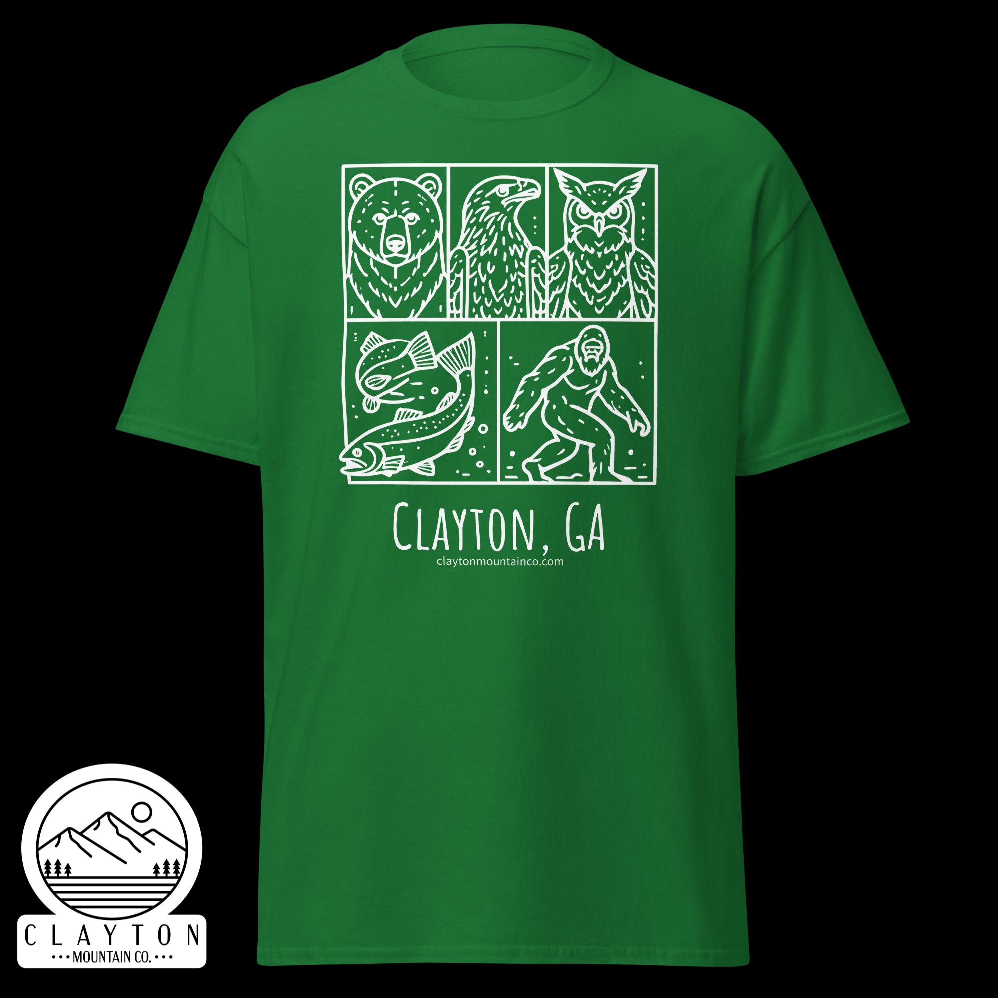 unisex-classic-tee-turf-green-front-6a2e6635b5f0bjpg - Clayton Mountain Co. Green t-shirt with a white four-panel mountain-themed graphic (bear, bird, fish, climber) and the text 'Clayton, GA' plus the site 'claytonmountainco.com' visible at the bottom.